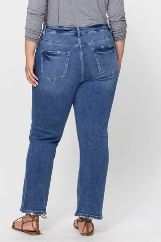 A person is shown from the back wearing Western Edge Boutique's Coop Curvy High Rise Stretch Slim Straight blue jeans and a gray long-sleeve shirt. The comfort stretch denim provides a slim straight fit, paired with brown sandals against a plain white background.