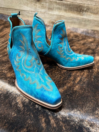 The Westerlee Turquoise Leather Booties from Western Edge Boutique are showcased on a rustic wooden surface. Made from soft leather, these booties feature intricate embroidery patterns, a pointed toe, and low wooden heels, effortlessly blending style and casual elegance.