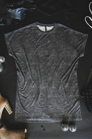 A 2FLY Wild West Cowboy T-shirt cowboy dress laid out on a black surface, surrounded by a variety of fashion items including a pair of tan ankle boots with metallic studs, silver disco balls, and a black bag with silver studs. The ensemble evokes a Wild Wild West vibe with sheer black fabric partially visible at the top.