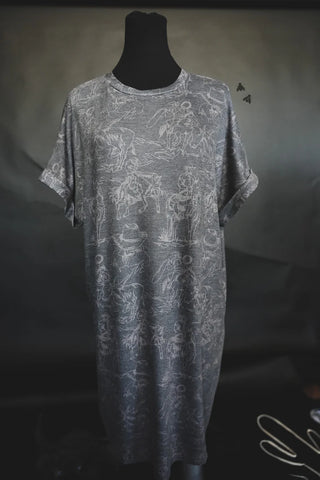 A black mannequin displays the Wild West Cowboy T-shirt dress by 2FLY, featuring short sleeves and a gray background. The dress showcases a white abstract line-art print depicting various figures and scenes inspired by the Wild Wild West. The plain, dark background accentuates the garment and its intricate design.