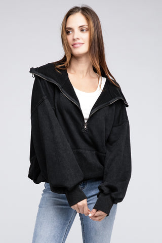 A woman with long brown hair, exuding effortless style, wears the Burke Quarter Zip Stitch Detailed Elastic Hem Hoodie from Western Edge Boutique over a white top and blue jeans. She stands against a plain gray background, looking to her right with a slight smile that suggests confidence in her fashion choice.