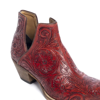A close-up of Myra's Moxie Hand-tooled Booties in Scarlet showcases their intricate floral engravings. These Western booties feature a wooden block heel and detailed craftsmanship, highlighting a hand-tooled pattern on the leather surface.