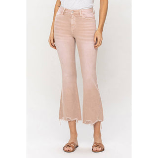 A person is wearing light pink Sparrow Vintage High Rise Stretch Denim jeans by VERVET by Flying Monkey, featuring frayed hems. The flared jeans are paired with a white top and brown sandals. The photo captures the individual from the shoulders down against a plain white background.