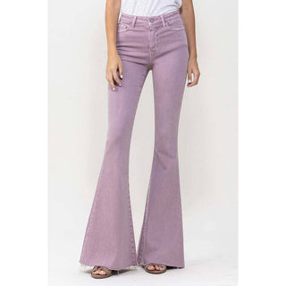 A person is wearing Violet High-Rise Super Flare Jeans by VERVET by Flying Monkey, paired with a tucked-in white top. The jeans feature a slightly distressed hem at the bottom. The person is standing against a plain white background, with only the lower half of their body visible.